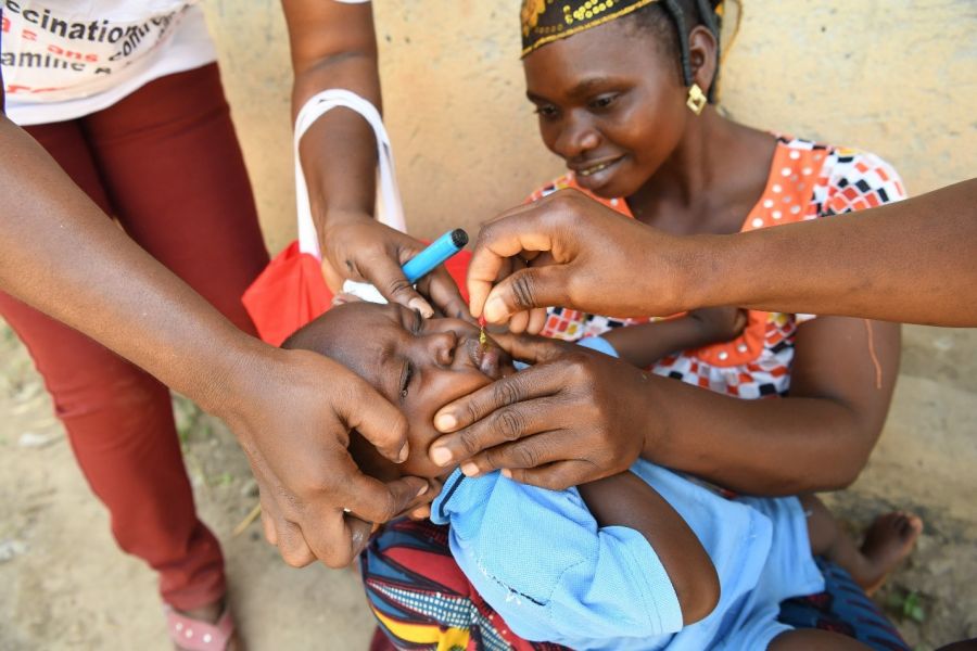 Mother holds child as he receives vitamin a drop.