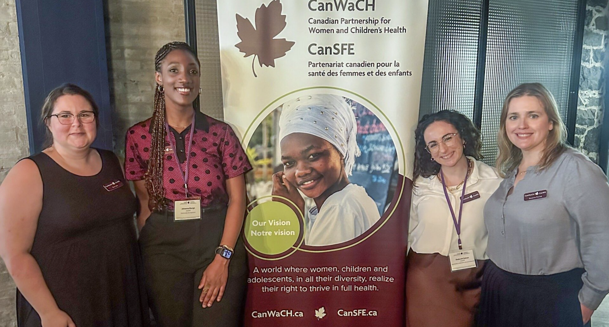 Two women smiling at an event booth with a CanSFE banner in the background.