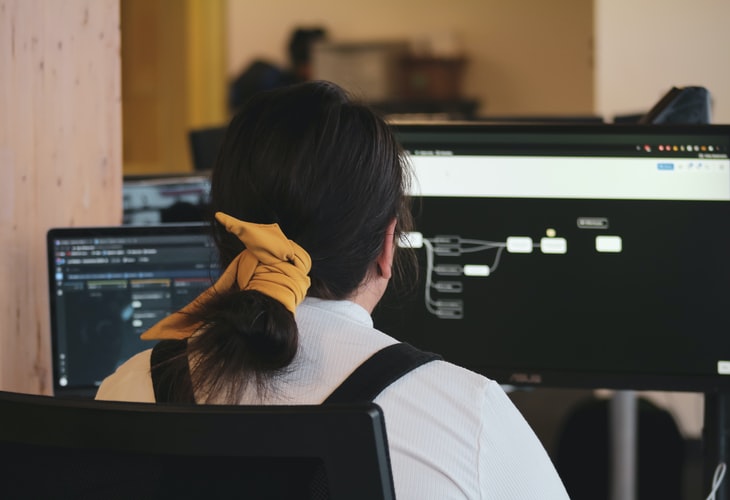 Person with hair in ponytail looking at data on a computer screen